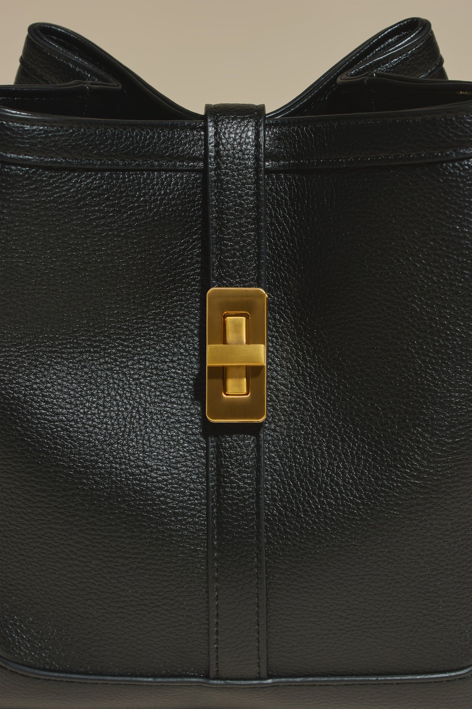 Close-up of black pebbled MJade material and brushed gold hardware.