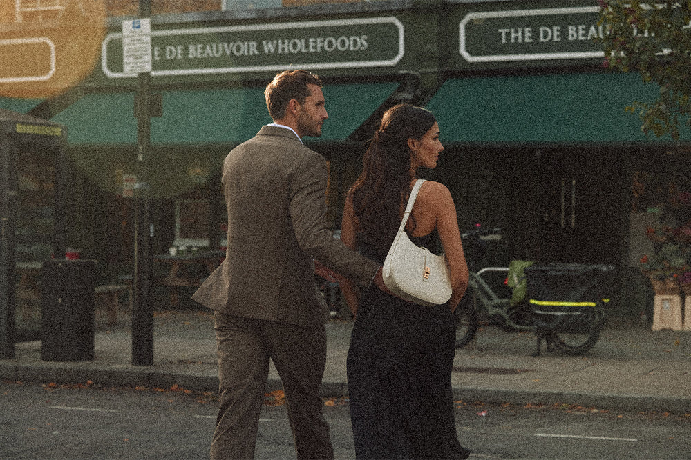 A couple walking past the De Beauvoir Deli with an ivory MJade handbag in London.