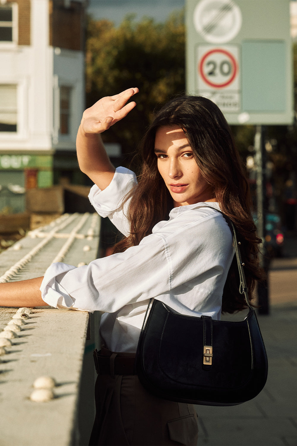 A woman carrying a black MJade handbag in the afternoon light on a London street.
