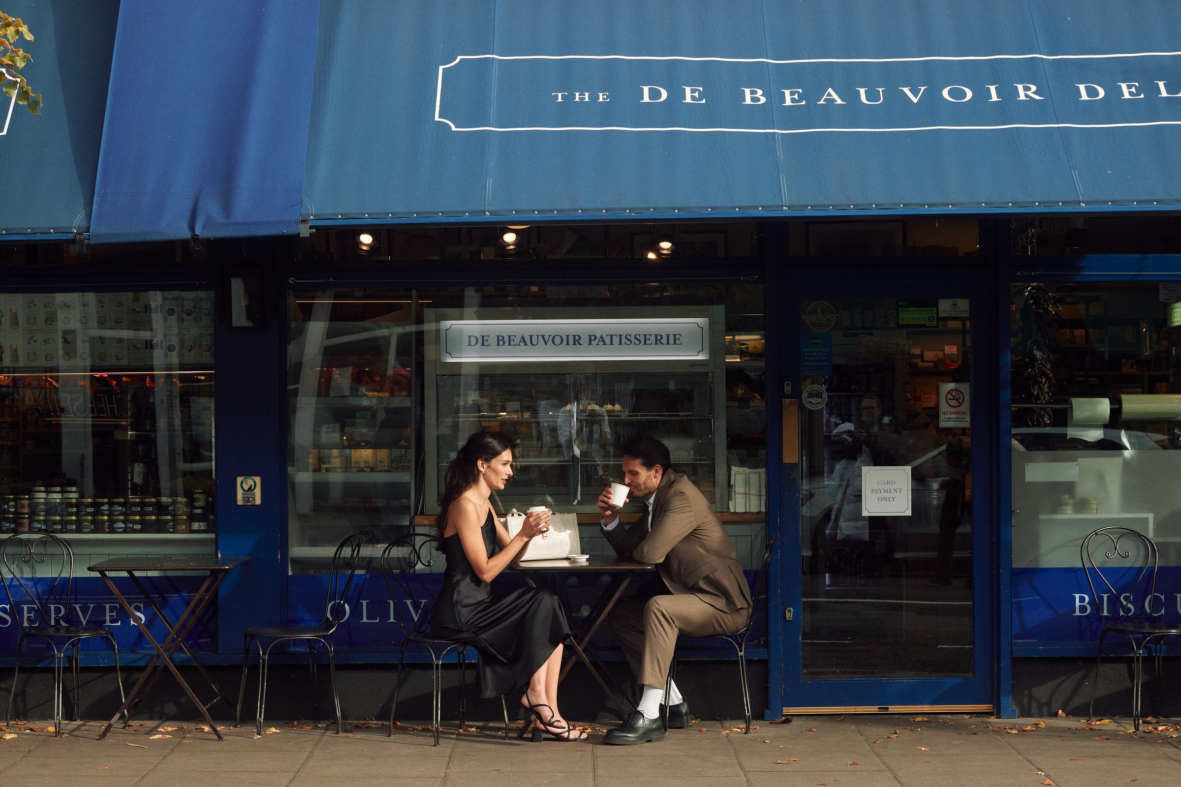 The De Beauvoir Deli in De Beauvoir Town, London, with the couple seated outside.