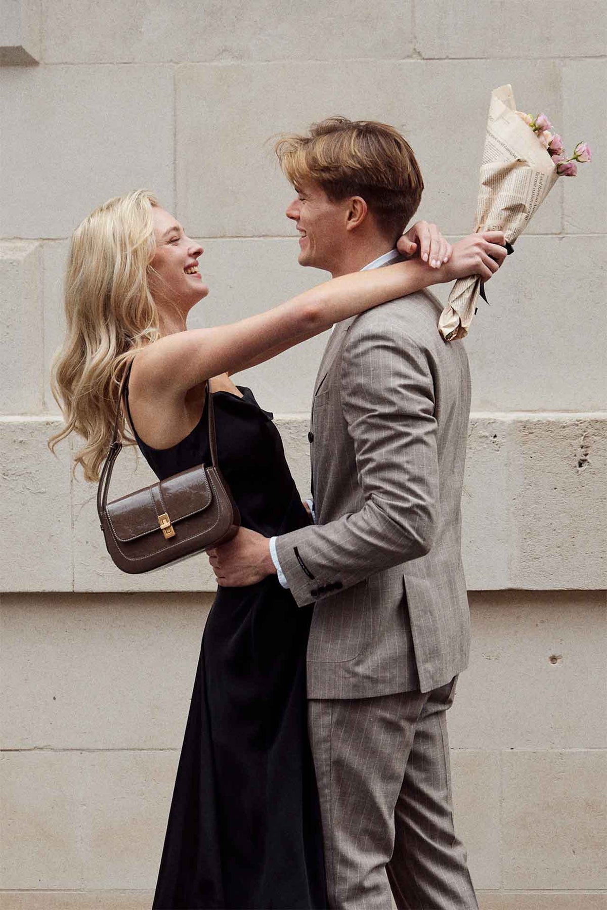 A woman adjusting her partner’s collar outside a London building.