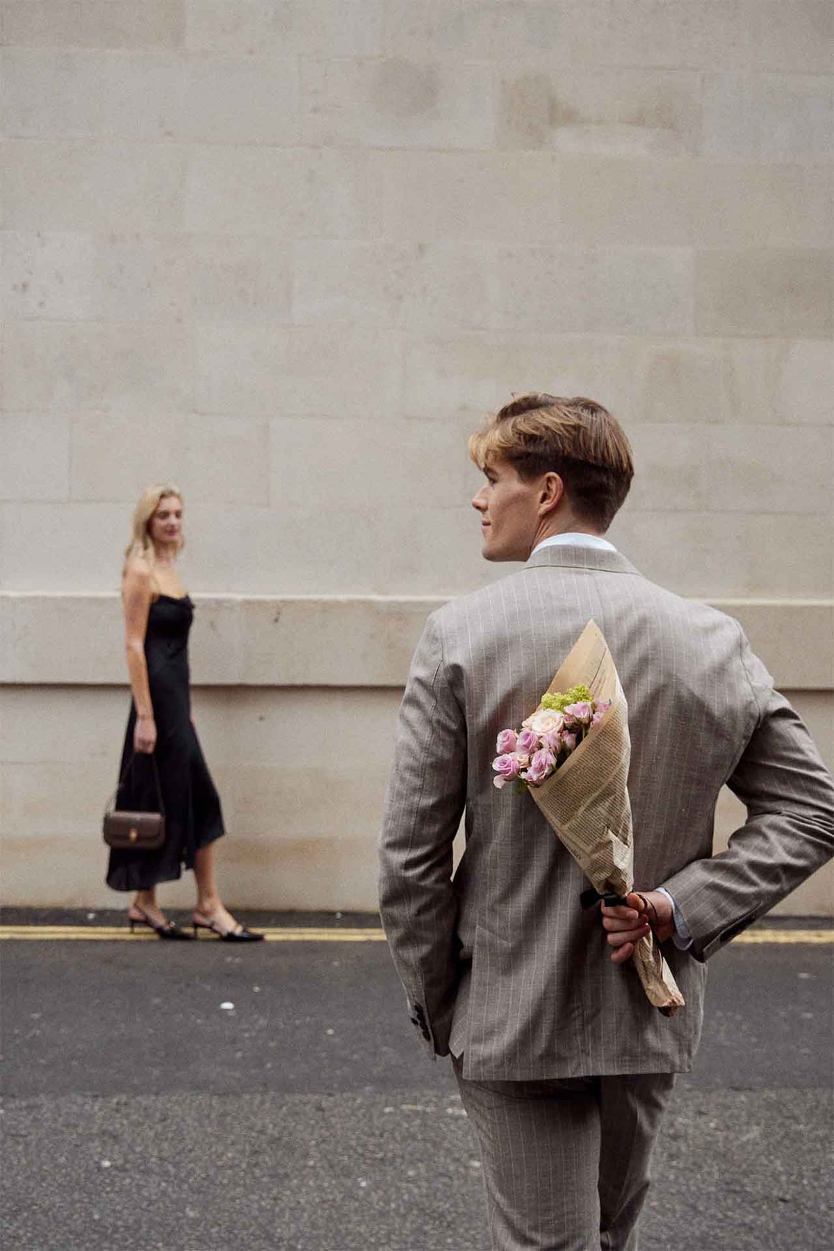 A couple embracing with flowers and a brown MJade handbag.