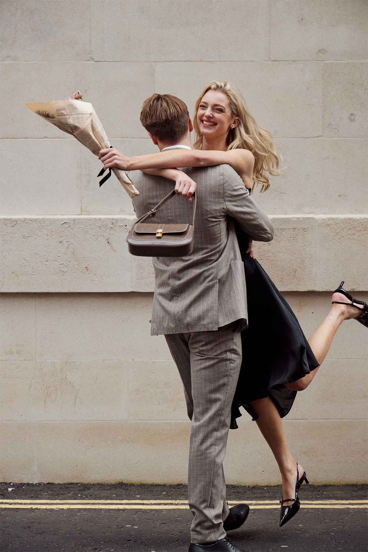 A man offering flowers to a woman carrying a brown MJade handbag.