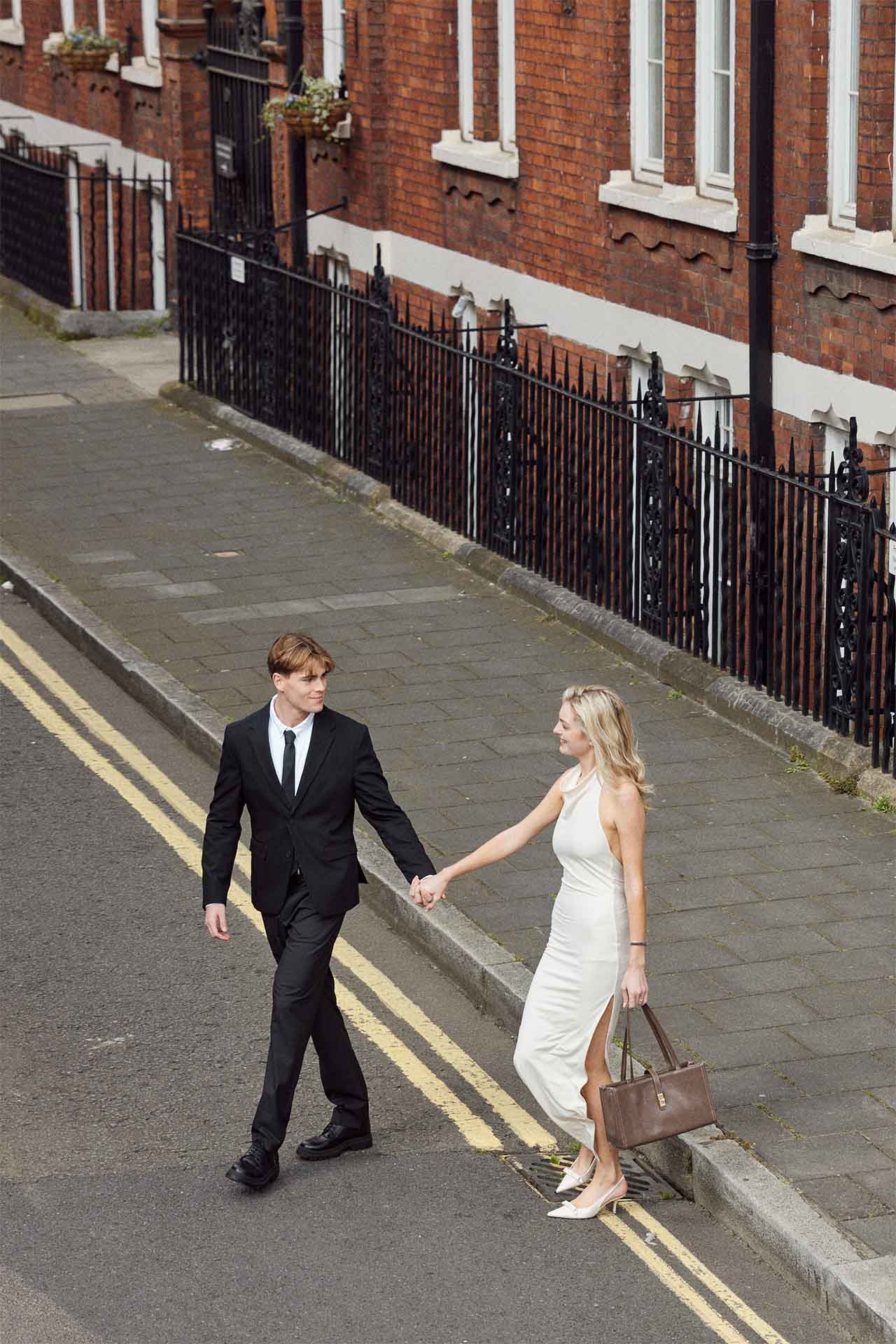 A woman reaching for her partner’s hand on a London residential street.