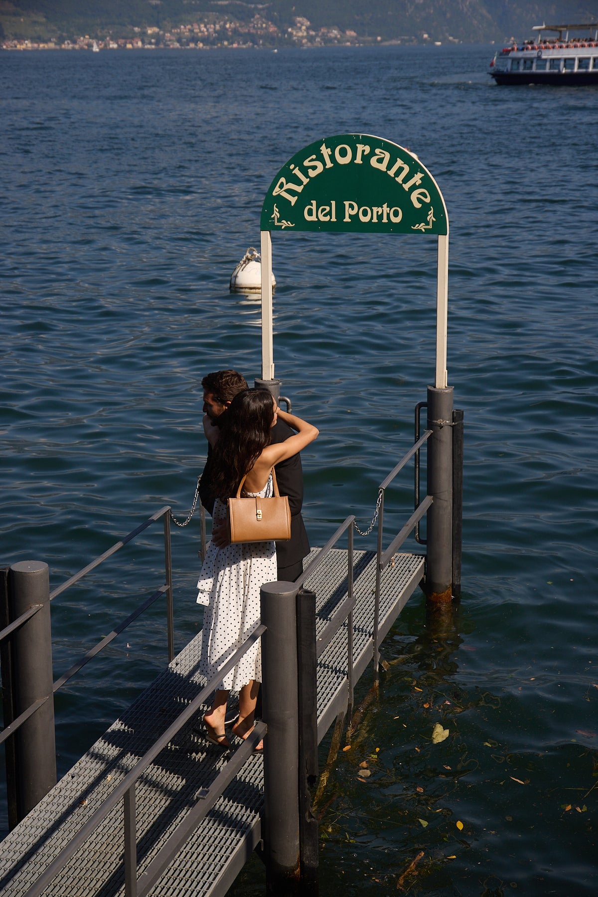 A couple embraces on a waterfront landing on Lake Como.