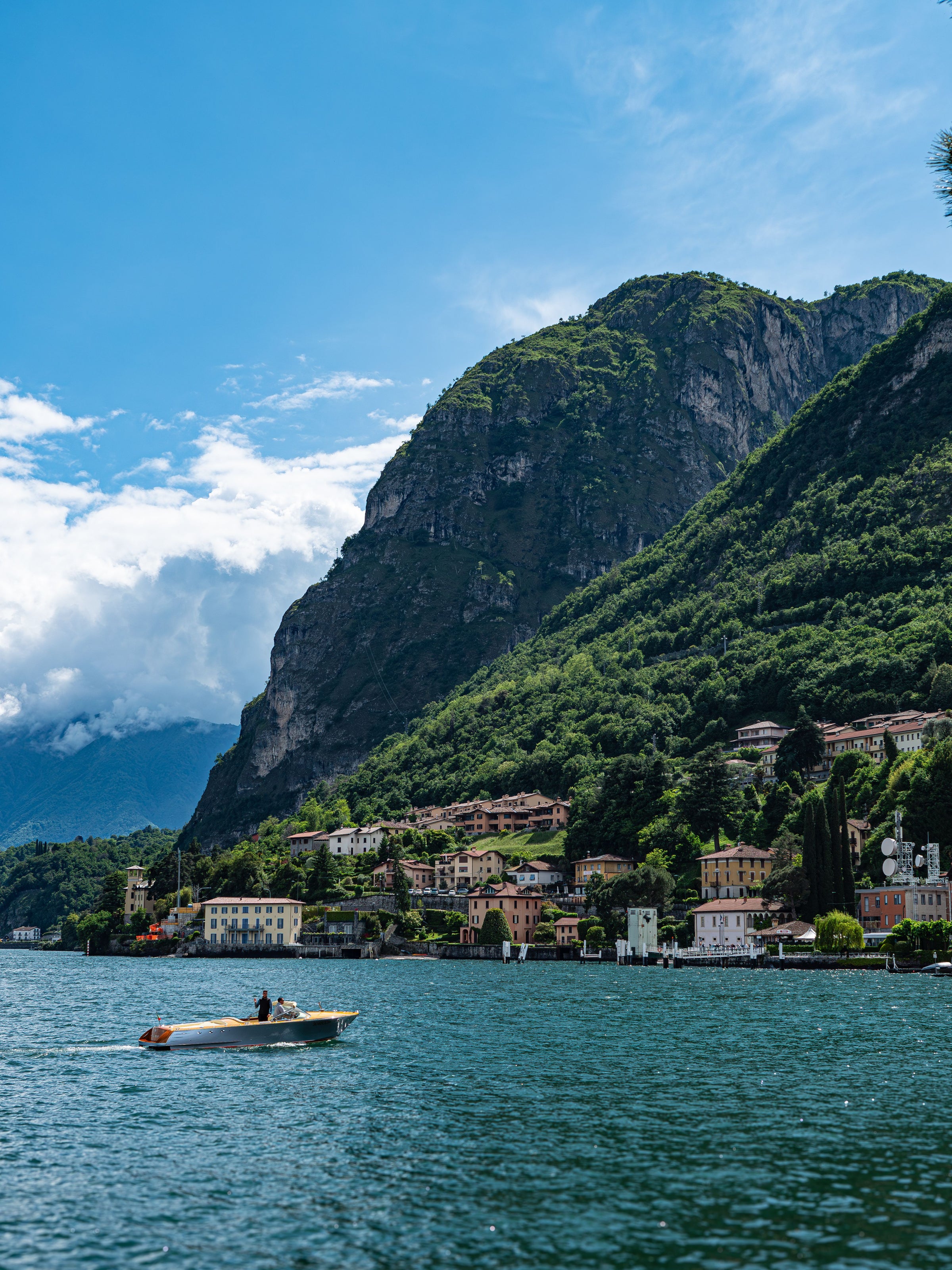A view across Lake Como from Menaggio, with mountains, shoreline and a small motorboat.