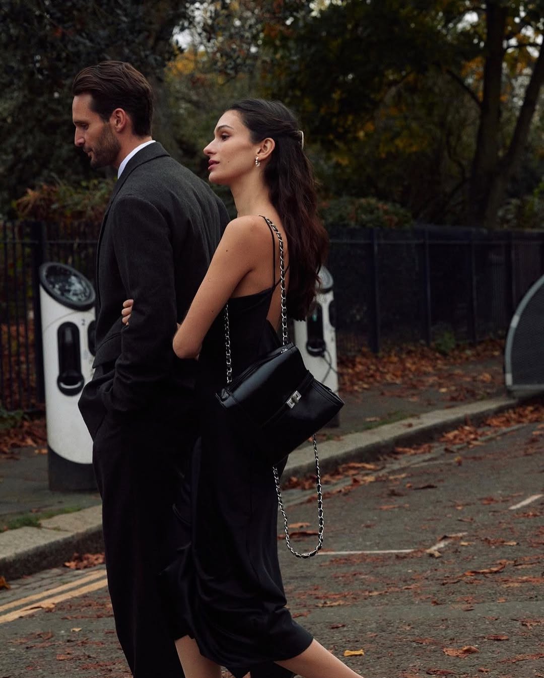 Woman carrying a black MJade chain-strap bag while walking outdoors.