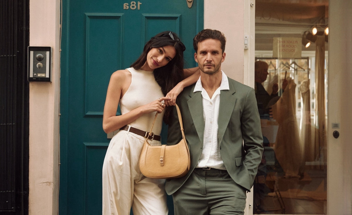 A contemporary couple standing together with an MJade handbag.